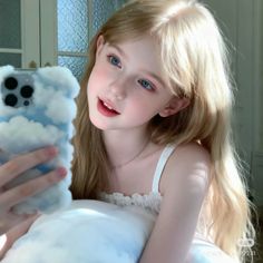 Young girl with blonde hair and blue eyes holding a phone with a cloud case