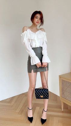 Woman in an off-shoulder top and mini skirt holding a quilted bag