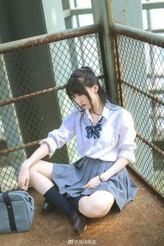 Woman in a school uniform sitting on a metal platform outdoors