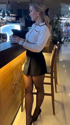 Woman with blonde hair in a mini skirt and high heels at a bar counter