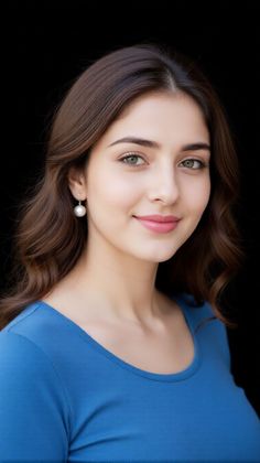Woman with long brown hair and green eyes wearing a blue shirt and pearl earrings