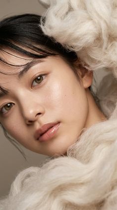 Close up portrait of a person with black hair and fluffy white material