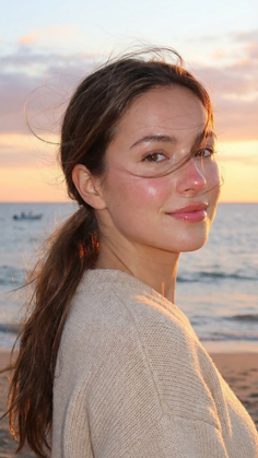 Woman with a ponytail on a beach at sunset with golden hour lighting