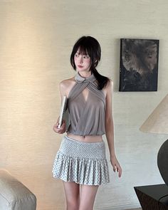 Woman in a halter top and mini skirt holding a book indoors