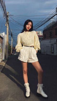 Woman in a cropped sweater and white shorts standing on a street