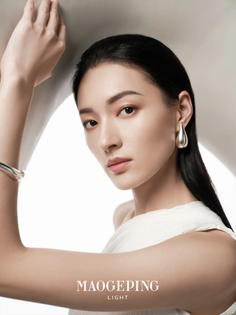 Woman with long black hair wearing a white top and silver jewelry