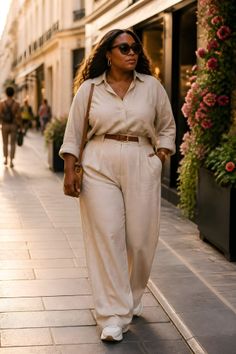 Woman in a neutral-toned outfit walking on a sunlit street