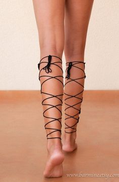 Bare legs with black laces wrapped around them, walking away from the camera