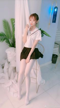 Woman in a school uniform and white tights sitting on a chair indoors