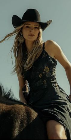 Woman in a cowboy hat and floral dress riding a horse outdoors