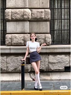 Woman in a white crop top and mini skirt with knee-high socks on a street