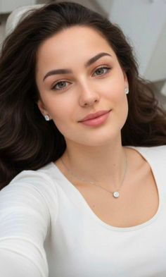 Woman with long dark hair wearing a white shirt and jewelry