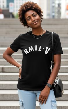 Woman with curly hair wearing a black t-shirt and light wash jeans outdoors