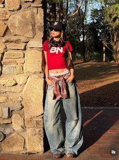 Woman in a red crop top and baggy jeans with a plaid shirt tied around her waist