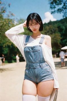 Woman in denim overalls and thigh-high socks outdoors on a sunny day