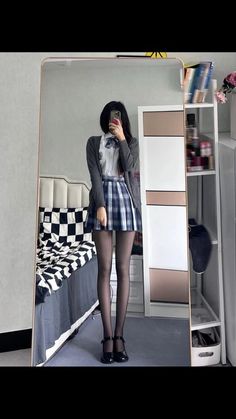 Person in a school uniform taking a mirror selfie in a bedroom