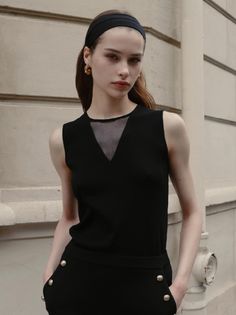 Woman with a black headband and gold earrings wearing a black top outdoors
