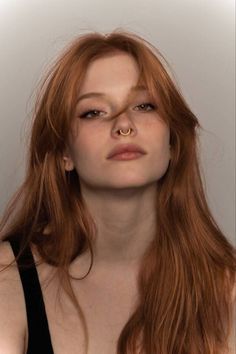 Woman with long red hair and a septum ring looking directly at the camera