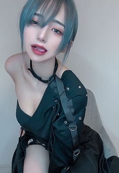 Woman with blue hair and black clothing in a provocative pose, showing cleavage