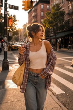Woman in a plaid shirt and crop top on a sunlit street at golden hour