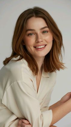 Smiling woman with short brown hair and green eyes in a collared shirt