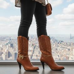 Person in cowboy boots and black jeans overlooking a cityscape