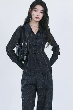 Woman with long dark hair wearing a dark patterned outfit and shoulder bag