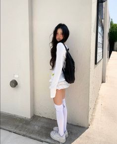 Young woman with long dark hair wearing a white top and mini skirt outdoors