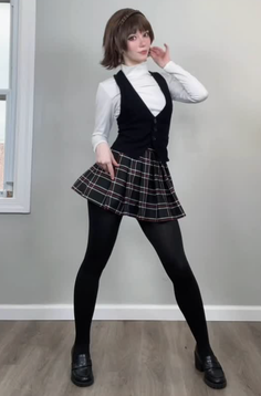 Person in a school uniform with a plaid skirt and black tights posing indoors