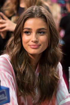 Woman with long wavy brown hair wearing a pink striped top