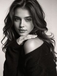 Woman with long wavy hair wearing an off-shoulder sweater in a black and white portrait