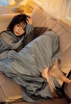 Woman in a grey dress relaxing on a couch indoors