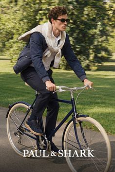 Man with curly hair and sunglasses riding a bicycle in a park