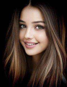 Smiling woman with long brown hair and green eyes against a dark background