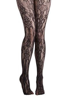 Pair of legs wearing black lace tights with a floral pattern