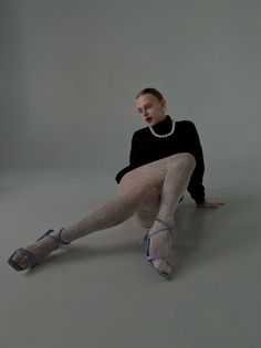 Woman in a black turtleneck and white lace tights posing in a studio