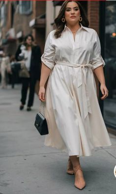 Woman in a cream midi dress and heels walking on a city street