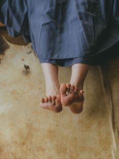 Bare feet of a person wearing a blue dress, with soft lighting