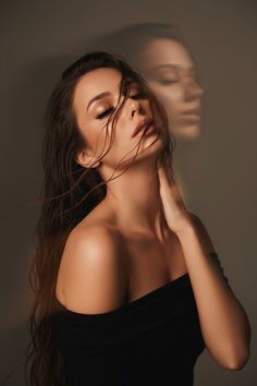 Woman with wet hair and an off-shoulder top, eyes closed, with a blurred reflection