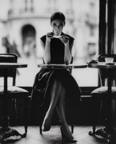 Woman in an elegant dress drinking coffee at a cafe table