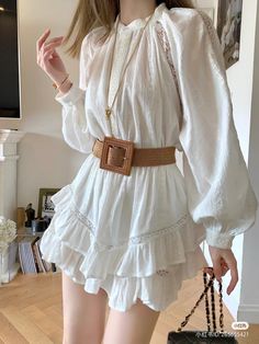 Woman in a white ruffle dress with a rattan belt and long sleeves