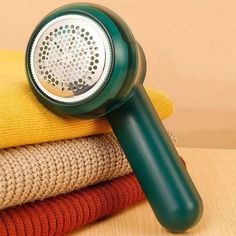 Green fabric shaver on a stack of colorful knitted sweaters