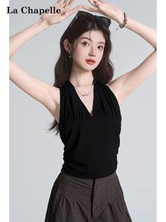Woman in a black halter top with sunglasses on her head posing in a studio