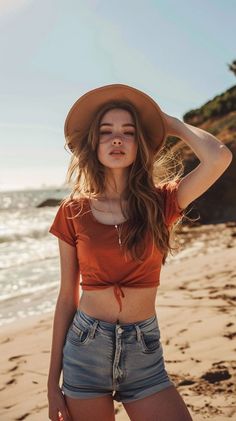Woman in a crop top and denim shorts on a beach at golden hour