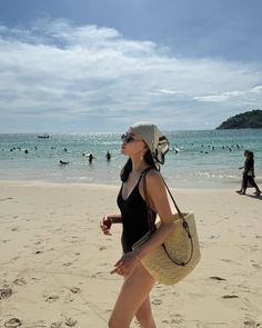 Woman in a black swimsuit and headscarf walking on a sunny beach