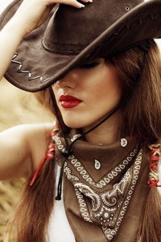 Woman in a cowboy hat and bandana with red lipstick and long brown hair