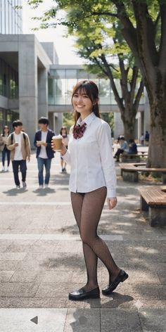 Woman in a school uniform shirt and fishnet stockings holding a cup outdoors