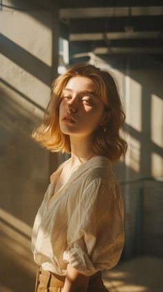 Woman with short blonde hair and freckles in a white shirt, lit by dramatic window light