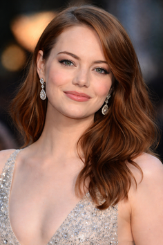 Woman with long red wavy hair and diamond earrings in a sparkling dress