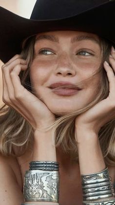 Woman with freckles and blonde hair wearing a cowboy hat and silver bracelets